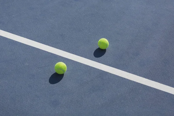 Balles de tennis sur le terrain dur bleu divisé par une ligne blanche — Photo