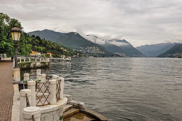 Vista a pé no Lago de Como e edifícios em um dia chuvoso nublado . — Fotografia de Stock