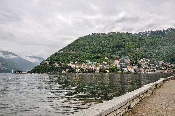 Vista a piedi sul Lago di Como e gli edifici in una giornata nuvolosa e piovosa . — Foto Stock