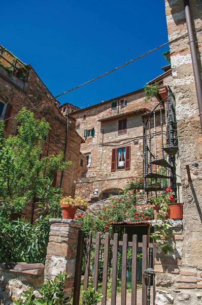 View of wooden gate, old buildings with flowering plants in Colle di Val d'Elsa — Stock Photo, Image