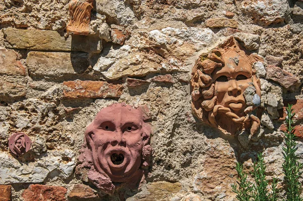 Közelkép az agyaggal maszkok csatolták a falra a Colle di Val d'Elsa. — Stock Fotó
