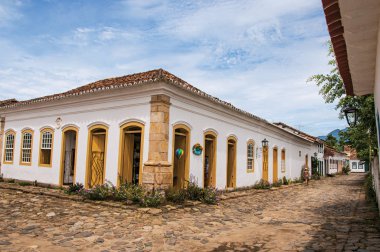 Arnavut kaldırımlı sokakta eski renkli evleri ve Paraty mavi bulutlu gökyüzü görünümü