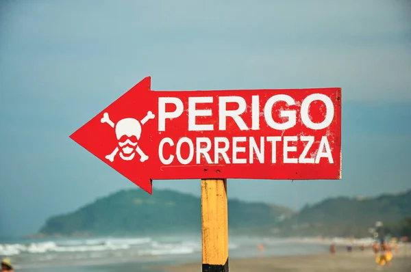 Primer plano de la señal de advertencia donde está escrito en portugués PELIGRO, CORRIENTE ", en la playa de Juquey — Foto de Stock