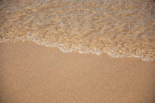 Vista de la ola del agua del mar rompiendo en la arena con el sol en la playa de Juquey —  Fotos de Stock
