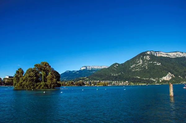 Άποψη της λίμνης Annecy, με το νησί, βλάστηση, στα βουνά και το μπλε του ουρανού στο παρασκήνιο. — Φωτογραφία Αρχείου
