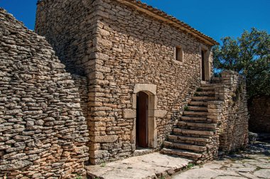 Merdiven ve güneşli mavi gökyüzünde, kasaba Gordes yakınındaki Bories köyü ile taştan yapılmış tipik ev.