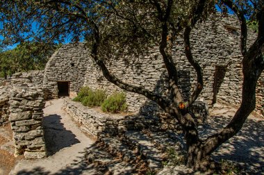 Yol ve Bories köy içinde güneşli mavi gökyüzü altında taştan yapılmış kulübe Gordes kasaba yakınlarında.