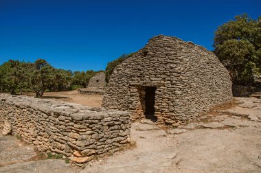 Yol ve Bories köy içinde güneşli mavi gökyüzü altında taştan yapılmış kulübe Gordes kasaba yakınlarında.