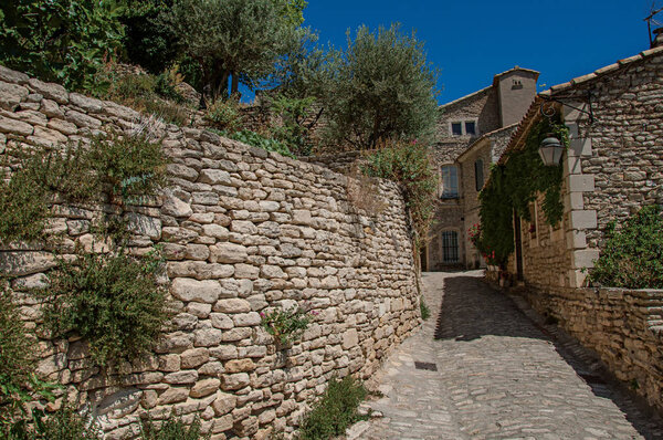 View of typical stone houses with sunny blue sky, in an alley of the historical city center of Gordes