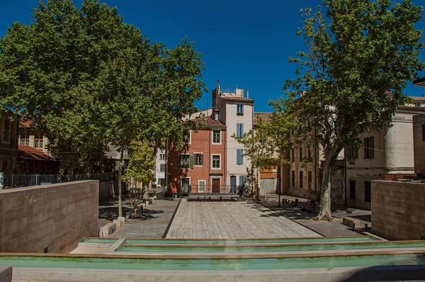 Place tranquille avec étang, arbres, bâtiments et ciel bleu dans le centre-ville de Nîmes . — Photo