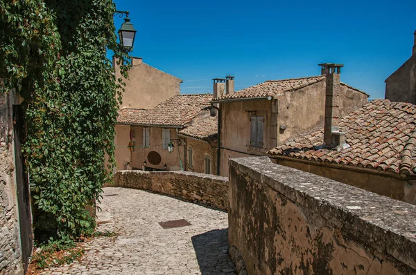 Veduta delle tipiche case in pietra con cielo azzurro e soleggiato, in un vicolo del borgo storico di Menerbes . — Foto Stock