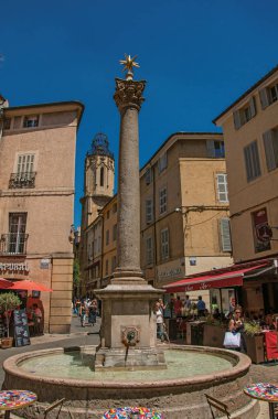 Kule, insanlar, mağazalar ve Aix-en-Provence çeşme ile çocuk arabası.