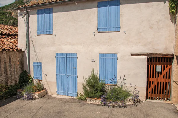 Visa av hus med blå fönsterluckor stängda i den charmiga byn Moustiers-Sainte-Marie. — Stockfoto