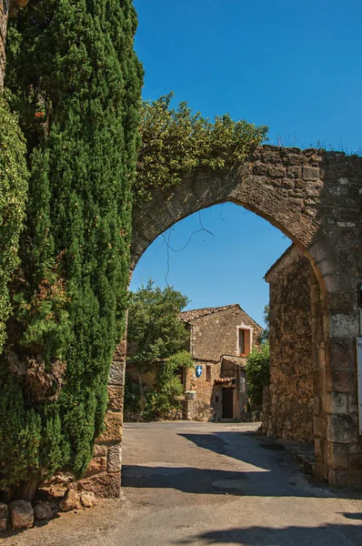 Veduta del muro di pietra e dell'arco sotto il cielo azzurro e soleggiato all'ingresso del grazioso borgo Les Arcs-sur-Argens . — Foto Stock