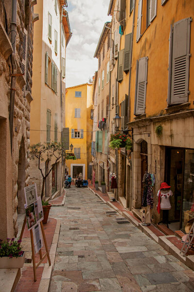 View of narrow street and buildings with shops in Grasse.