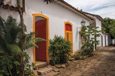 Paraty, Brezilya - 26 Ocak 2015. Eski renkli evleri ve Paraty, Rio de Janeiro devlet sahil tamamen korunmuş bir şaşırtıcı ve tarihi kasaba bitki örtüsü ile Arnavut kaldırımlı sokak görünümü