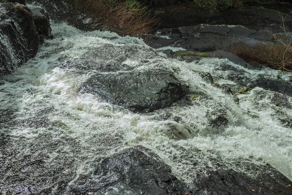 Espuma e água correndo rápido através de rochas — Fotografia de Stock
