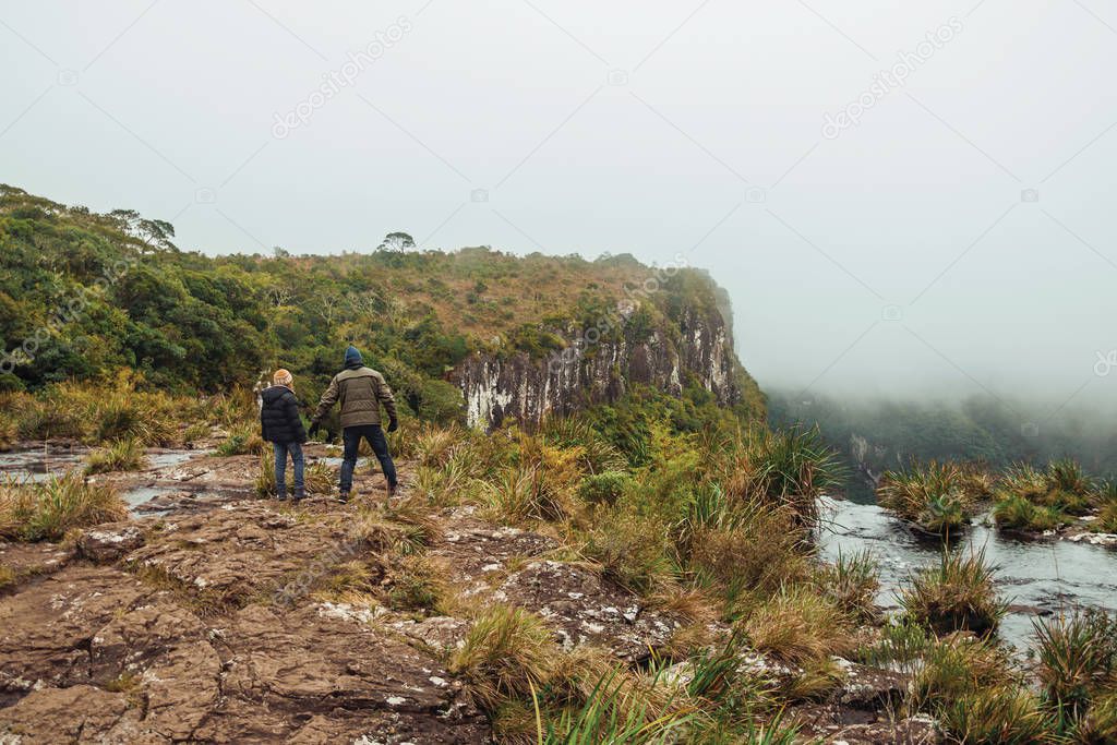 People on the edge of rocky cliff and mist