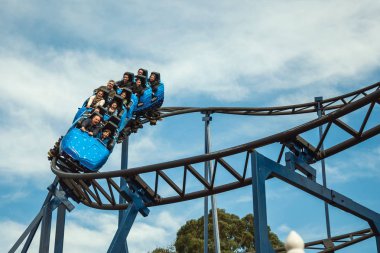 İnsanlar lunapark treninde eğleniyor.