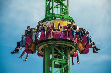 İnsanlar lunaparkta eğleniyor.
