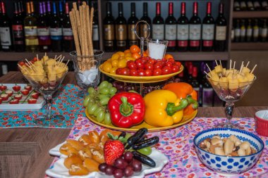 Platters and bowls with appetizer among decorative fruits and vegetables in a wine shop of Sao Paulo. The gigantic city, famous for its cultural and business vocation. Southeast Brazil. clipart