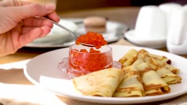 Kırmızı havyarlı gözleme. Kadın eli kaşıkta kırmızı havyarı topluyor. Shrovetide için gözleme.