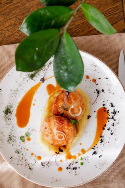 Güzel beyaz bir tabakta pirzola ile patates püresi. Tabak mikro-yeşilliklerle süslenmiş. İçerideki ahşap bir masanın arka planına karşı..