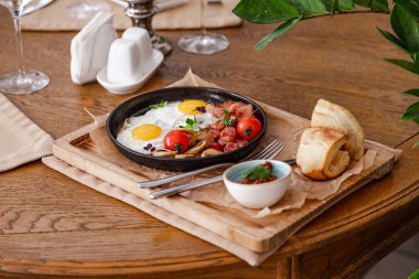 İngiliz kahvaltısı. Kızarmış sosisli yumurta, pastırma, domates ve mantar. Fasulye ezmeli bir ahşap üzerinde.