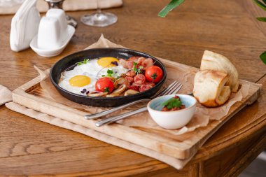 İngiliz kahvaltısı. Kızarmış sosisli yumurta, pastırma, domates ve mantar. Fasulye ezmeli bir ahşap üzerinde.