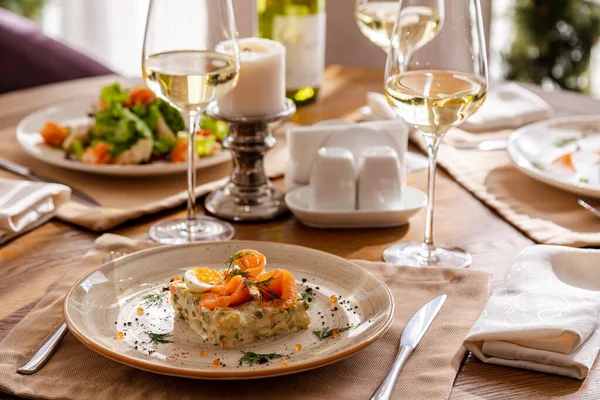 Tabaklarla servis edildi. Masanın üzerinde karides salatası, olivier salatası köfteli patates püresi ve İngiliz kahvaltısı var. Yemek için beyaz şarap servis edilir..