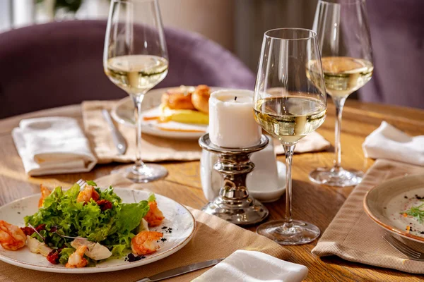 Tabaklarla servis edildi. Masanın üzerinde karides salatası, olivier salatası köfteli patates püresi ve İngiliz kahvaltısı var. Yemek için beyaz şarap servis edilir..