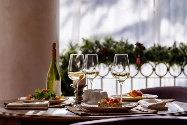 Mesa servida con platos. En la mesa hay ensalada de camarones, ensalada olivier, puré de papas con albóndigas y un desayuno inglés. El vino blanco se sirve para la comida . — Foto de Stock