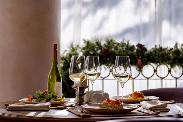 Table servie avec vaisselle. Sur la table se trouvent une salade de crevettes, une salade d'olivier, de la purée de pommes de terre aux boulettes de viande et un petit déjeuner anglais. Le vin blanc est servi pour le repas . — Photo