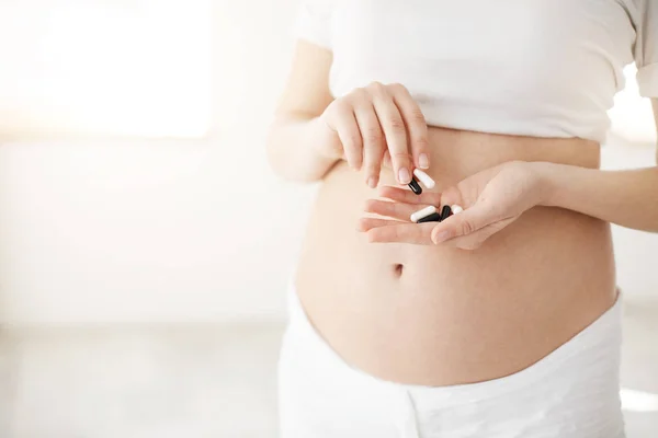Yakında anne holding ilaç ve ilaç veya vitamin olmak Closeup hamile. Sağlıklı annelik kavramı. Yüksek anahtar. — Stok fotoğraf