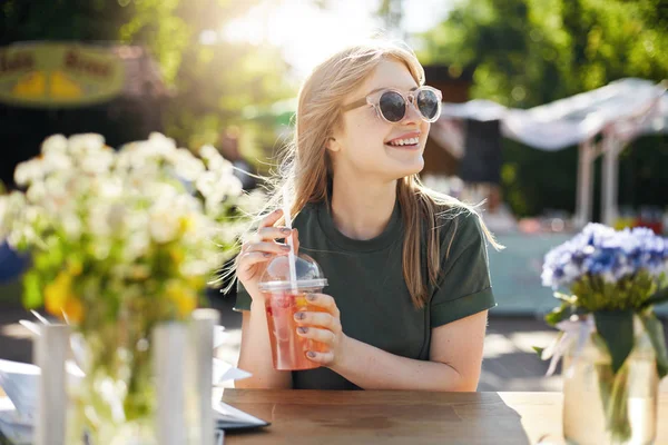 Retrato de uma jovem blogueira de comida feminina bebendo limonada usando óculos e sorrindo . — Fotografia de Stock