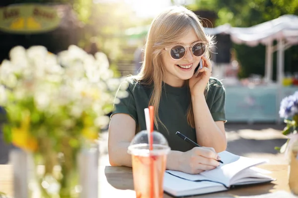 Portrét mladé ženy nebo student psaní její plány v programu Poznámkový blok na smartphone s úsměvem nosíš brýle přestávce luch v parku za slunečného letního dne. — Stock fotografie