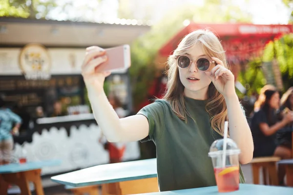 Blondes sommersprossiges Mädchen macht ein Selfie mit Brille, um es an einem Sommertag im Park in den sozialen Medien zu posten. — Stockfoto