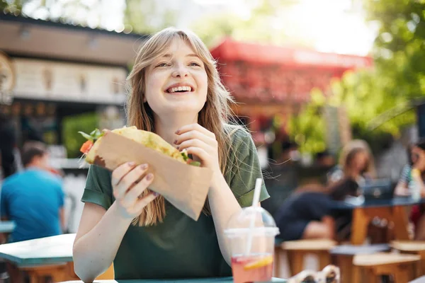 Gadis makan taco. Wanita pirang berbintik-bintik lapar memegang makanan cepat saji di tempat makan pada hari musim panas yang cerah di taman sambil tersenyum menikmati makanannya . — Stok Foto