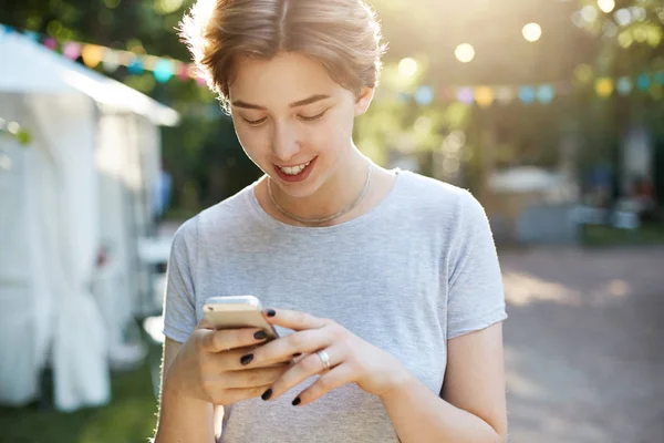 Mädchen mit Smartphone. Porträt einer jungen Hipster-Frau, die ein modernes Smartphone im Freien nutzt, SMS schreibt oder durch die sozialen Medien scrollt oder mit einem Freund ein Gespräch führt. — Stockfoto