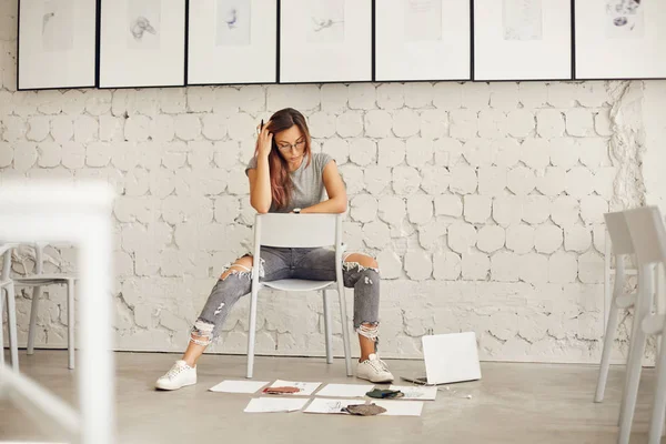 Diseñadora de moda aspirante pensando en textiles y bocetos esparcidos en el suelo de hormigón en su nuevo espacio de estudio —  Fotos de Stock