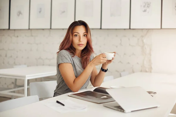 Genç kadın girişimci bir iş alarak kırmak bir açık alan hub oturan veya içme kahve kameraya bakarak coworking — Stok fotoğraf