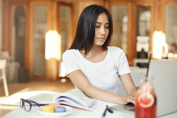 Estudiante asiática trabajando en una computadora portátil en el campus, preparándose para su diploma o navegando por las redes sociales. Concepto educativo . — Foto de Stock