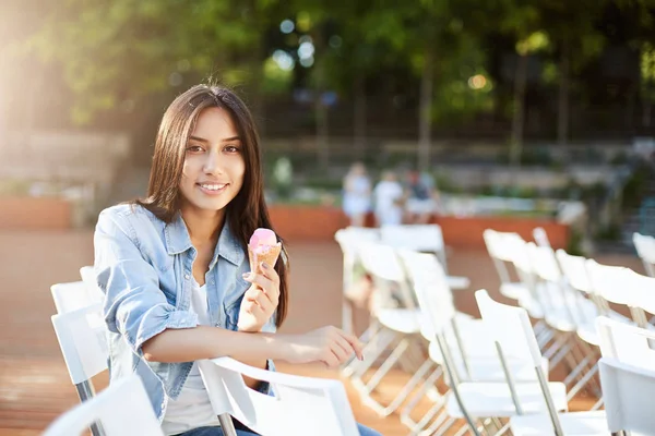 Mladá východní žena jíst zmrzlinu venku v městském parku nebo koncertní aréna čekání na spuštění. Životní styl koncept. — Stock fotografie