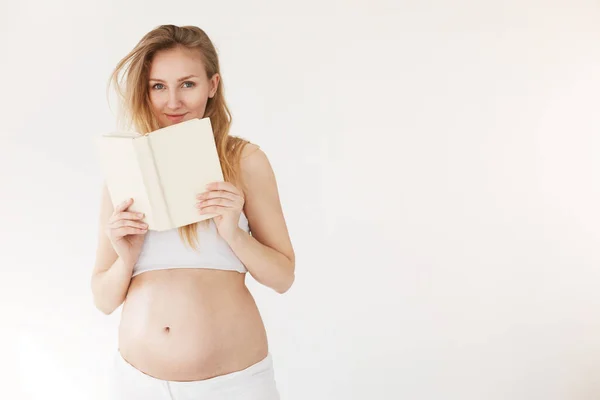 Donna incinta che legge un libro sul cibo sano e l'allattamento al seno o semplicemente rilassarsi prendendo il suo tempo in congedo di maternità . — Foto Stock