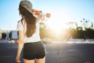 Bayan kaykaycı onun longboard paten bir aramada bir kentsel ortamda spot bir güneşli yaz gününde holding.