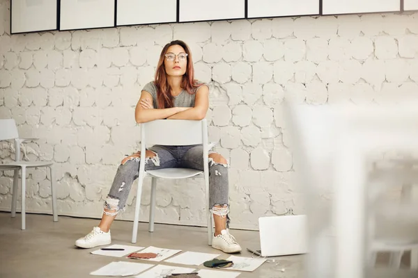 Potret perancang busana wanita dikelilingi oleh pekerjaannya yang duduk di ruang studio memimpikan proyek baru — Stok Foto