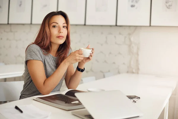 Jonge schrijver ontspannen drinken koffie afromen via tijdschrift in een mooie studio ruimte. — Stockfoto