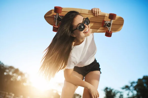Aktives Porträt einer Skateboarderin, die sich auf die Kamera stützt und ihr langes Brett zum Abspringen bereit hält — Stockfoto