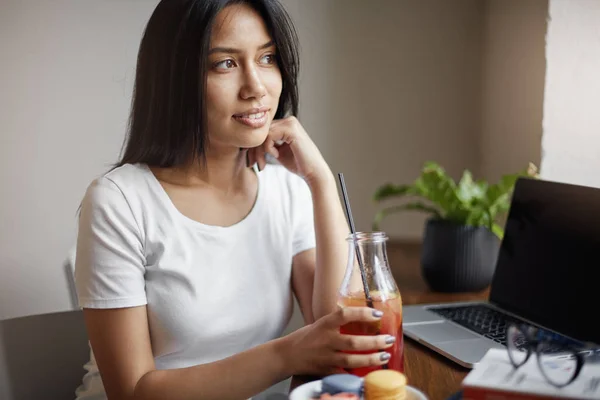 Giovane asiatico femmina bere limonata in caffè utilizzando laptop . — Foto Stock