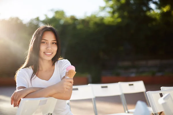 Mladá žena jíst zmrzlinu v parku přestávce letní vzdělávání při pohledu na fotoaparát s úsměvem — Stock fotografie